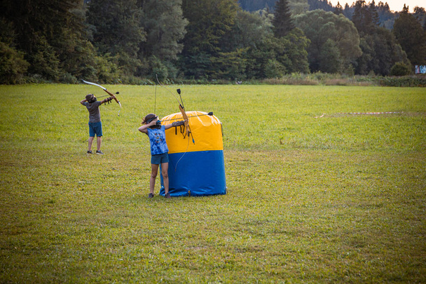 Klein meisje schieten een pijl uit een boog tijdens een spel van boogschieten tag - Foto, afbeelding