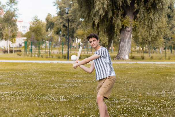 adolescente chico sosteniendo softball bat y jugando béisbol en parque - Foto, imagen