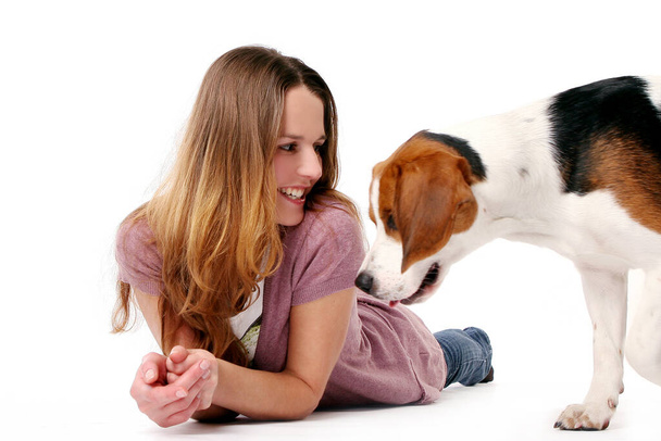 Ευτυχισμένη νεαρή γυναίκα παίζει με το σκύλο της σε λευκό φόντο  - Φωτογραφία, εικόνα