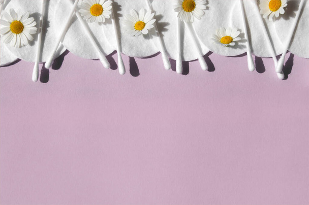 Ear sticks, white cotton pads and romomiles on a pink background with copy space. Концепция гигиены и личной гигиены тела. - Фото, изображение