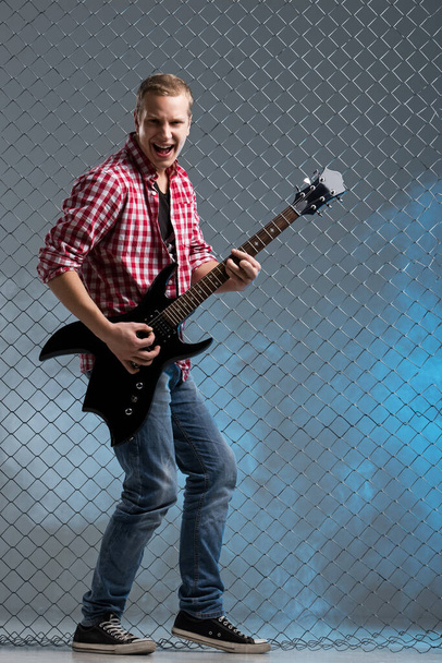 Zene, hang. Zenész egy gitár kerítés háttér - Fotó, kép