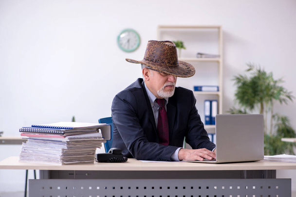 Funny old boss in cowboy hat in the office - Photo, Image