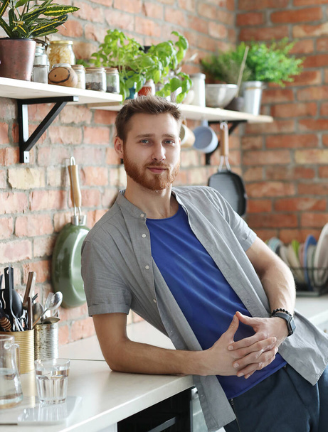 Komea nuori mies, jolla on parta poseeraa keittiössä - Valokuva, kuva