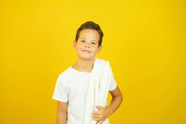 Niño con una toalla de hacer deporte sobre fondo amarillo - Foto, imagen