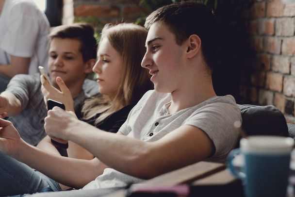 Группа подростков развлекается и пользуется смартфонами дома
 - Фото, изображение