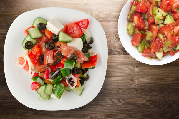 Greek salad on brown wooden background . Greek salad on white plate with vegetarian salad top view . healthy food - Фото, зображення