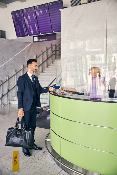 Mannelijke reiziger geeft zijn documenten aan luchthavenpersoneel - Foto, afbeelding