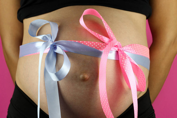 Pregnant belly with blue and pink ribbons - Zdjęcie, obraz