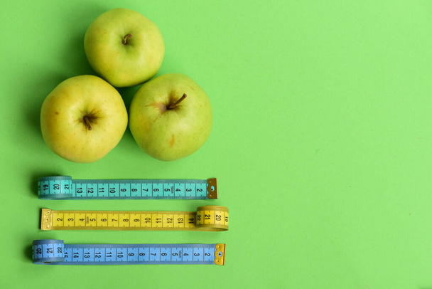 Sports and healthy lifestyle symbols. Apples near measuring tape rolls - Foto, immagini