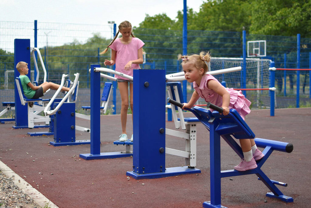children on sports simulators at outdoor site. sportive family on training - 写真・画像