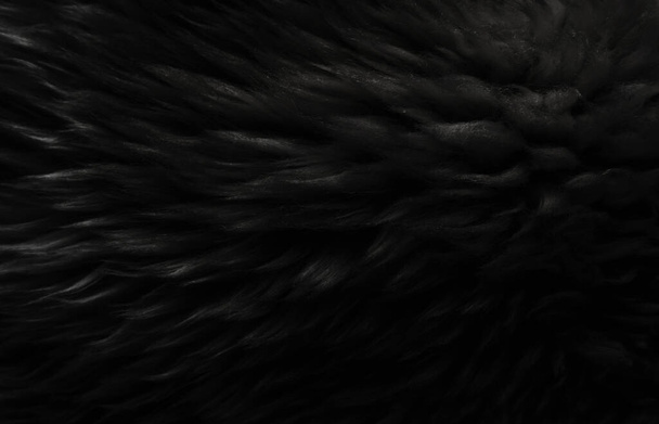 Tierische Textur aus schwarzer Wolle, beiger, flauschiger Fellhintergrund, dunkles Naturhaar, Nahaufnahme - Foto, Bild