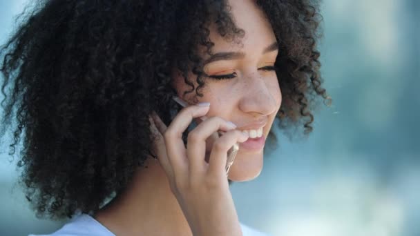 Joven atractiva mujer afroamericana hablando en el teléfono móvil al aire libre - Metraje, vídeo