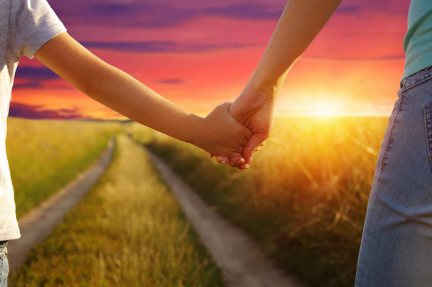 Руки держат друг друга в поле на дороге и солнце - Фото, изображение