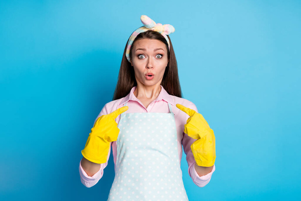 Портрет здивованої дівчини вказує індекс пальців латексних рукавичок сама вражена, що вона вибирає рішення носити рожеву сорочку ізольовано на синьому кольорі
 - Фото, зображення