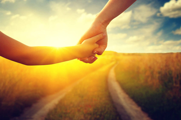 Hands of holding each other in field on road and sun - Photo, Image