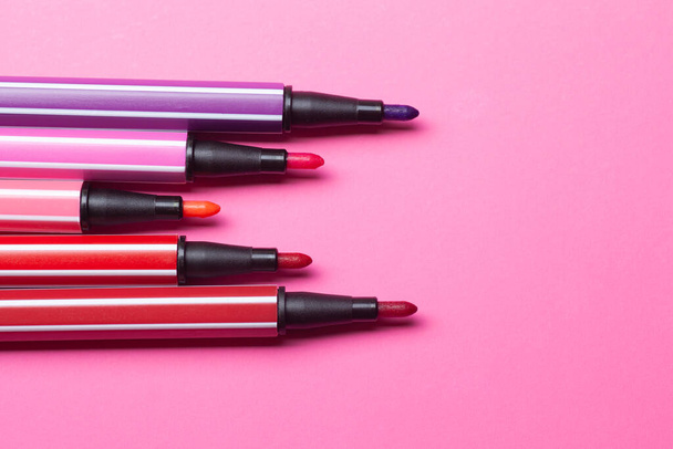пять открытых маркеров или ручки розового, фиолетового, розового цвета лежат как шаги на розовом фоне, изолированные макет - Фото, изображение