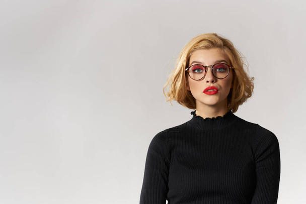 Blonde girl with glasses red lips black blouse cropped view glamor light background studio - Fotoğraf, Görsel