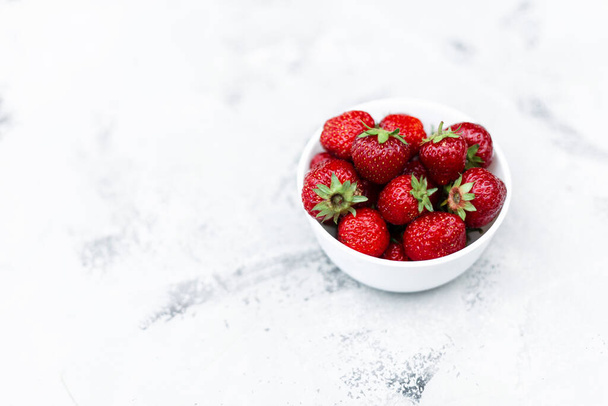 Juicy tasty strawberries in a white plate on the table - Fotó, kép