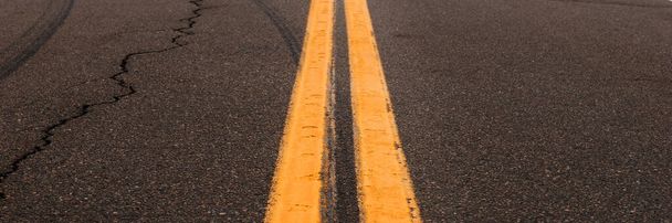 2つの黄色の道路線とアスファルトの背景。アスファルト上の道路標識 - 写真・画像