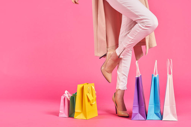 Einkaufstaschen weibliche Füße in Schuhen Shopaholic rosa Hintergrund - Foto, Bild