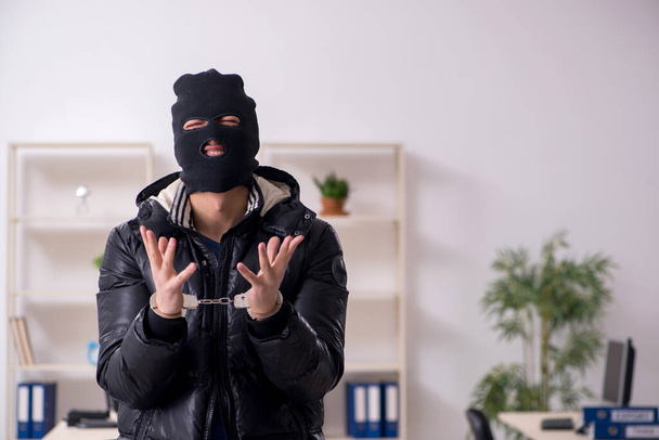 Молодий чоловік грабіжник в офісі
 - Фото, зображення