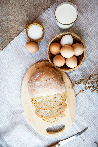 Csendélet kenyér tej tojás és só fából készült lemezek, a háttérben meleg színekben. - Fotó, kép