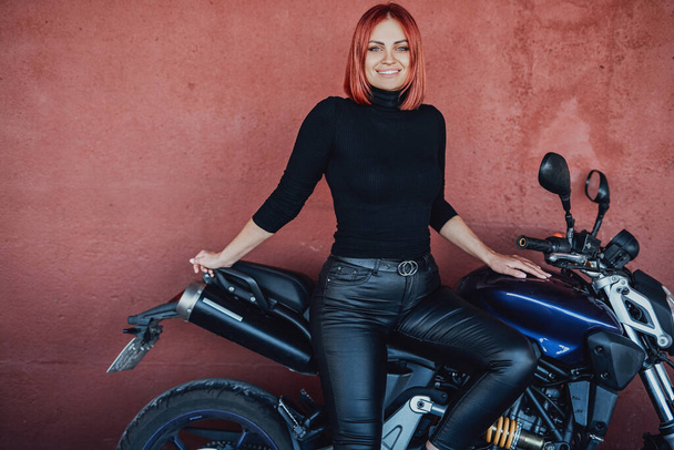 An attractive girl with red hairs sitting on her urban bike - Photo, Image