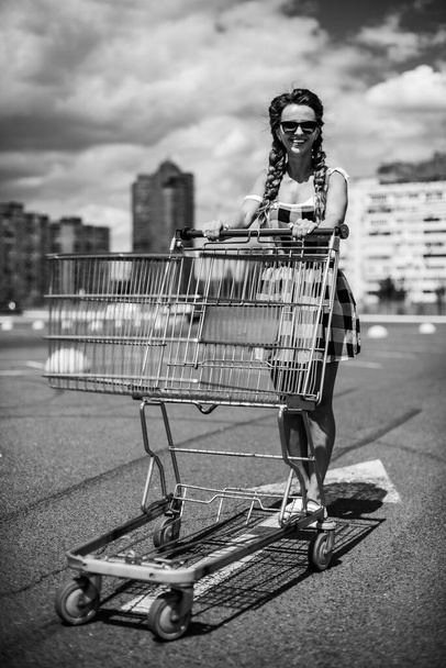 Supermarktwagen. Een vrouw draagt een trolley naar een supermarkt.. - Foto, afbeelding