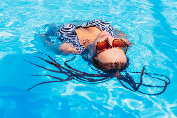 Swimming pool. Sportive woman in a swimsuit swims in the pool. Portrait. - Foto, imagen