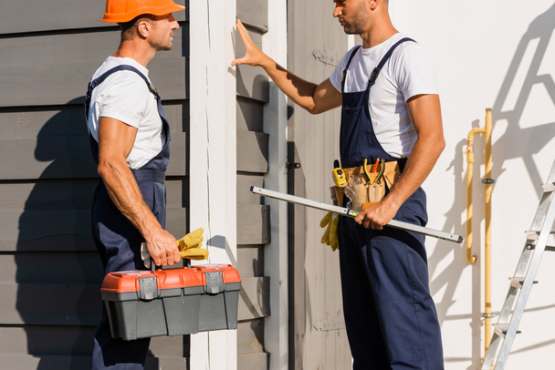 Builders with tools and toolbox standing near facade of building  - Photo, Image