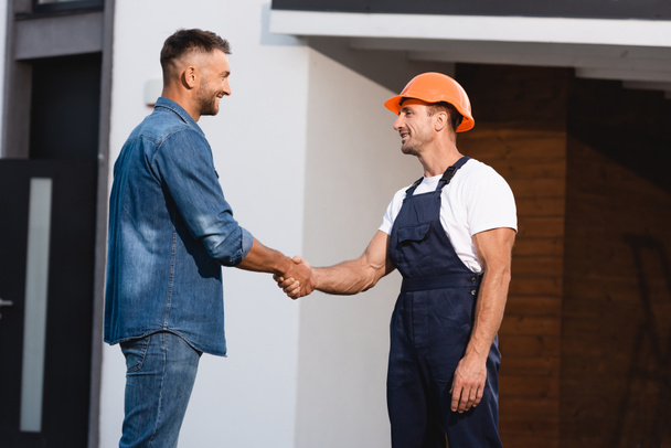 Man shaking hands with builder in uniform near building  - Photo, Image