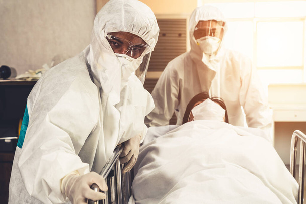 Notarzt und Arzt bringen den Patienten in die Notaufnahme des Krankenhauses. Arzt trägt Schutzanzug und Gesichtsmaske im Konzept von Coronavirus und Covid 19 Schutz und Quarantäne . - Foto, Bild