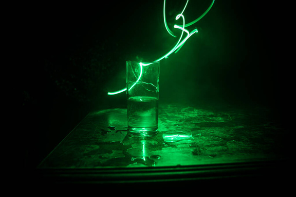 Πιες, σπασμένο γυαλί. Σπασμένα γυαλιά σε ξύλινο τραπέζι σε σκούρο τονισμένο φόντο με ομίχλη. Επιλεκτική εστίαση - Φωτογραφία, εικόνα