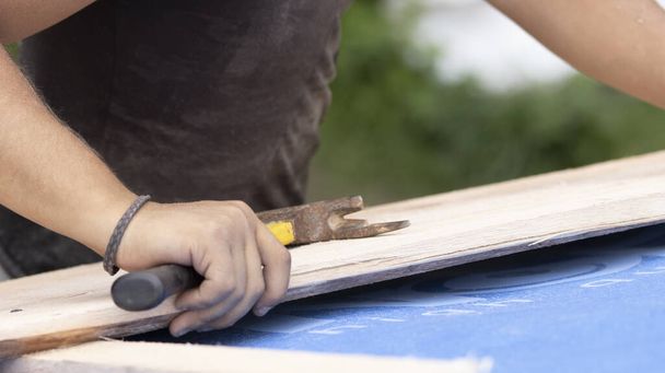 Ο εργάτης ετοιμάζει ένα ρόπαλο για να καρφώσει στην οροφή.. - Φωτογραφία, εικόνα