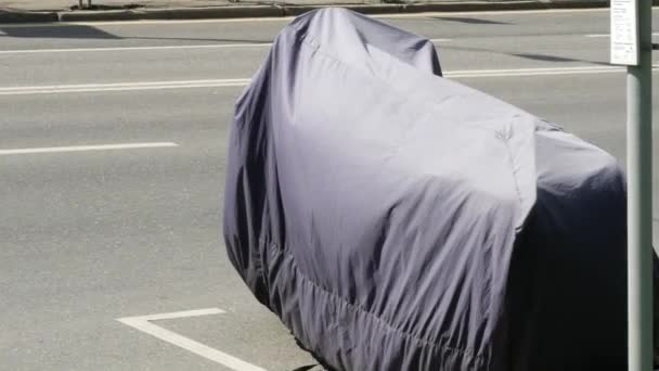 Motorcycle parked on  road and covered with protective tarpaulin. Cover on - Footage, Video