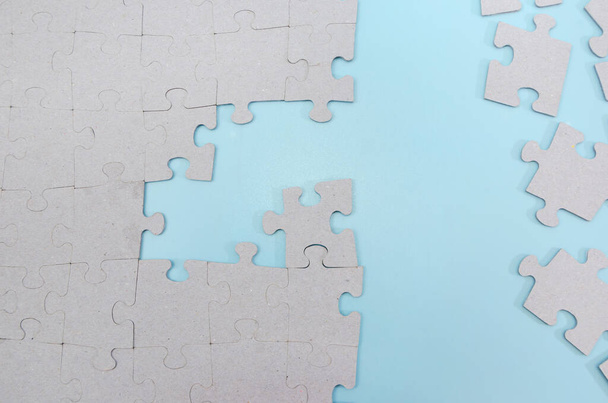 Unfinished gray puzzle pieces on a blue background. business idea. - Foto, imagen
