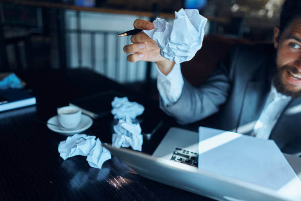Üzletember egy kávézóban ül az asztalnál dokumentumok laptop gyűrött papír végrehajtó életmód érzelmek - Fotó, kép