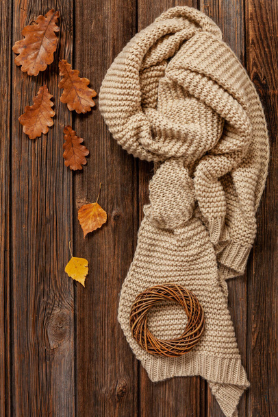 Warm scarf and autumn leaves. Autumn background, top view, close-up on wooden vintage table. - Фото, зображення