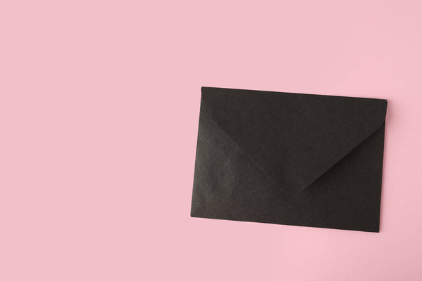 Black paper envelope on pink background, top view. Space for text - 写真・画像