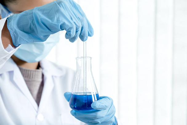 Вчені тримають скляну трубку, наповнену синьою хімічною рідиною для дослідження та аналізу в лабораторії
. - Фото, зображення