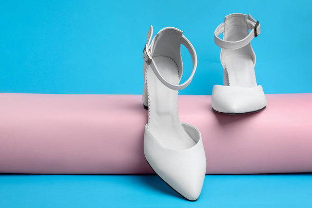 Stylish white female shoes on light blue background - Foto, Imagen