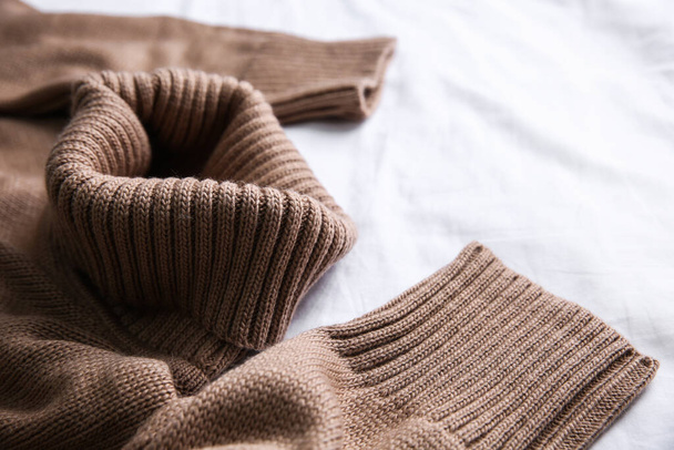Brown warm sweater on white crumpled fabric, closeup - Fotoğraf, Görsel