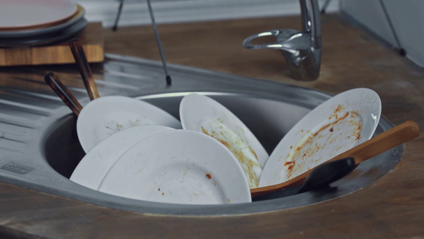 Piatti sporchi e utensili da cucina nel lavello della cucina  - Filmati, video