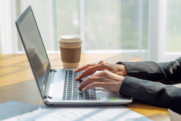 Close-up de uma mulher de negócios mãos digitando em um laptop no escritório com xícara de café, conceito de negócio - Foto, Imagem