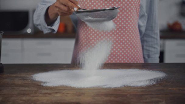 Movimiento lento de la mujer sembrando harina en la mesa de la cocina  - Metraje, vídeo