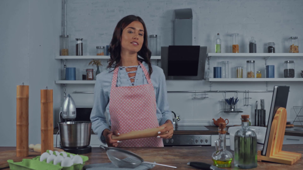 Nainen elehtii ja puhuu kameran edessä ruoanlaitossa keittiössä  - Materiaali, video