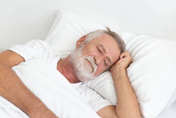 Preocupado jubilado mayor acostado en su cama - Foto, imagen