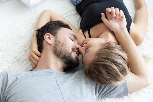 Krásný šťastný pár v lásce, úsměv, a políbit navzájem na posteli v ložnici - Fotografie, Obrázek