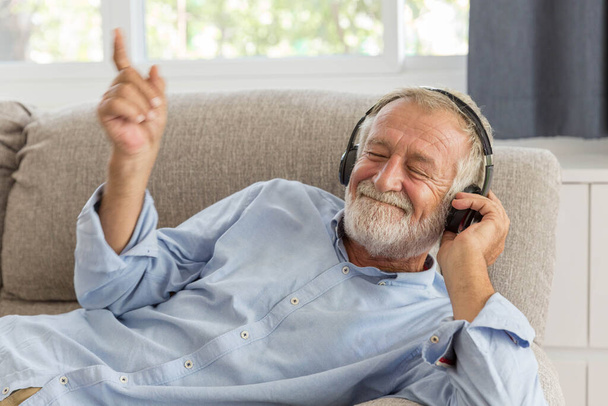 Nyugdíjas férfi zenét hallgat fejhallgatóval, boldog otthon. - Fotó, kép