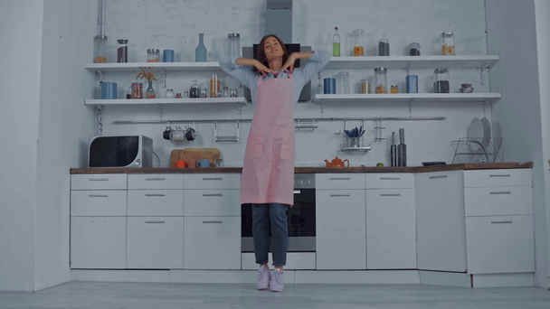 Junge Frau in Schürze tanzt in Küche  - Filmmaterial, Video